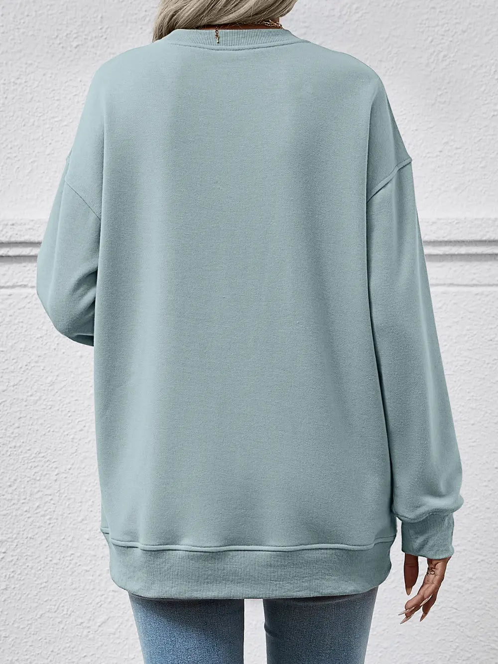 Light blue sweatshirt worn by a person against a light gray wall
