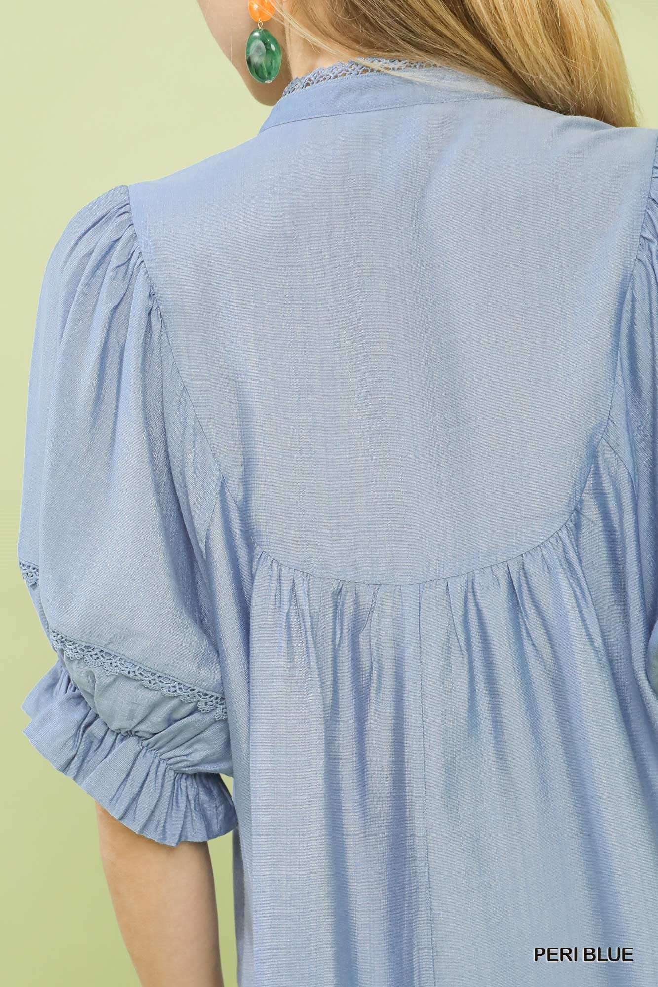 Light blue dress with ruffled sleeves on a person against a light green background