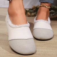 White slippers with fuzzy trim worn indoors on a wooden floor.
