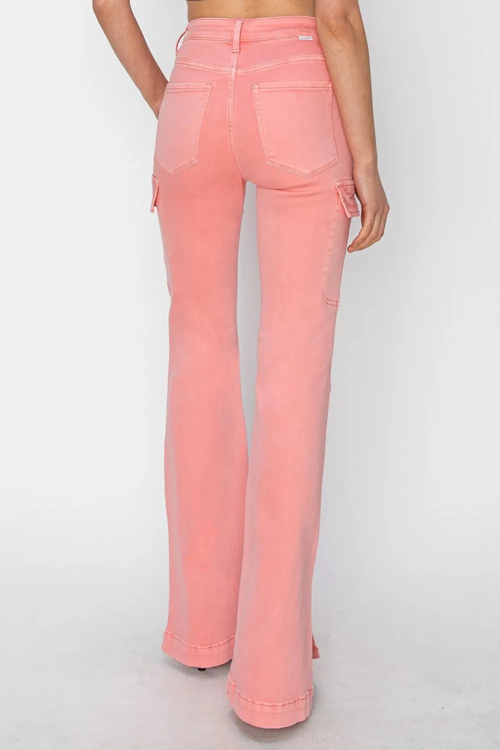 Person wearing pink flared jeans on a white background