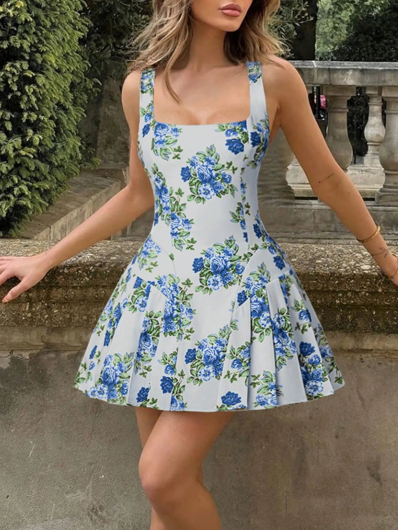 Woman wearing a floral dress standing outdoors near stone steps.