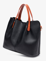 Black handbag with orange handles on a light gray background