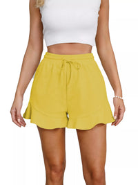 Yellow shorts worn by a person on a white background