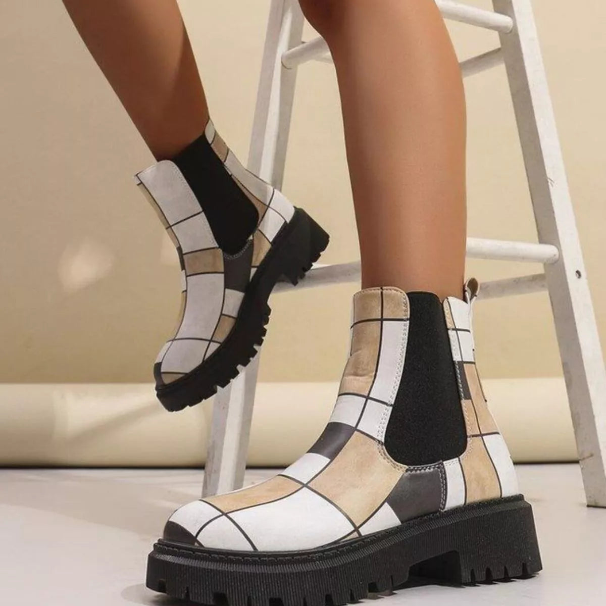 Patterned boots worn by a person sitting on a chair with a neutral background