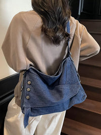 Person wearing a beige jacket and carrying a blue denim bag.