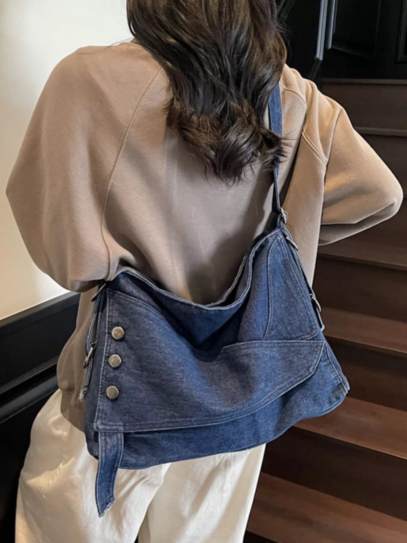Person wearing a beige jacket and carrying a blue denim bag.