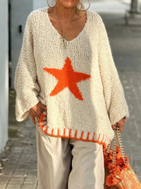 Person wearing a beige sweater with an orange star design, holding an orange bag.