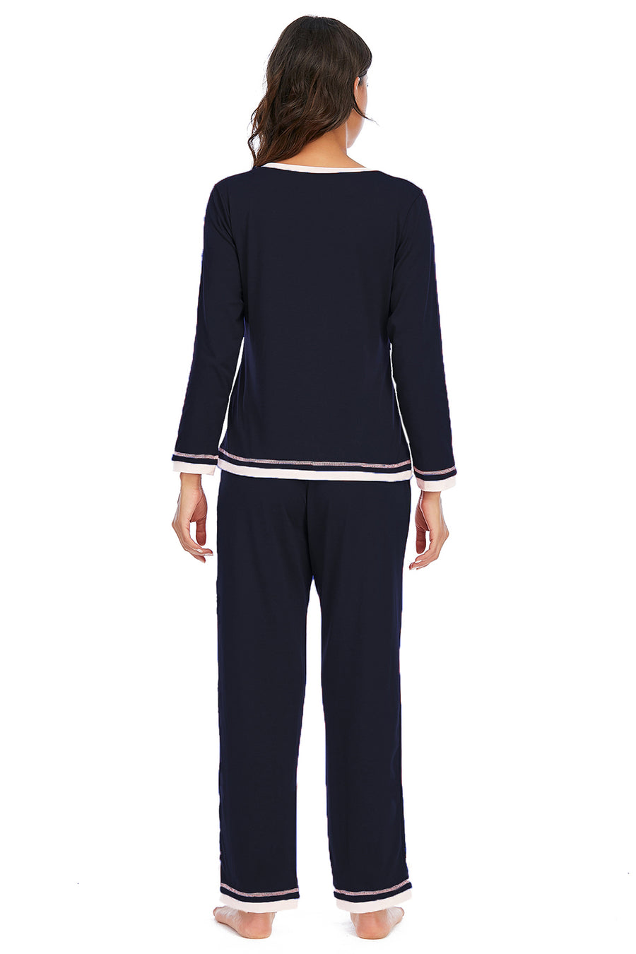Woman wearing a navy blue pajama set with white trim on a white background