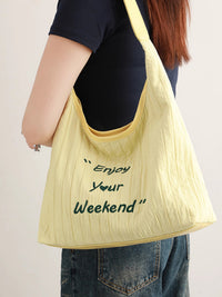 Yellow tote bag with 'Enjoy Your Weekend' text held by a person against a plain background
