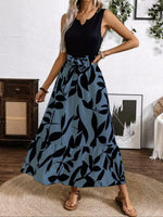 Woman wearing a black top and blue leaf-patterned skirt in a room with decor elements.