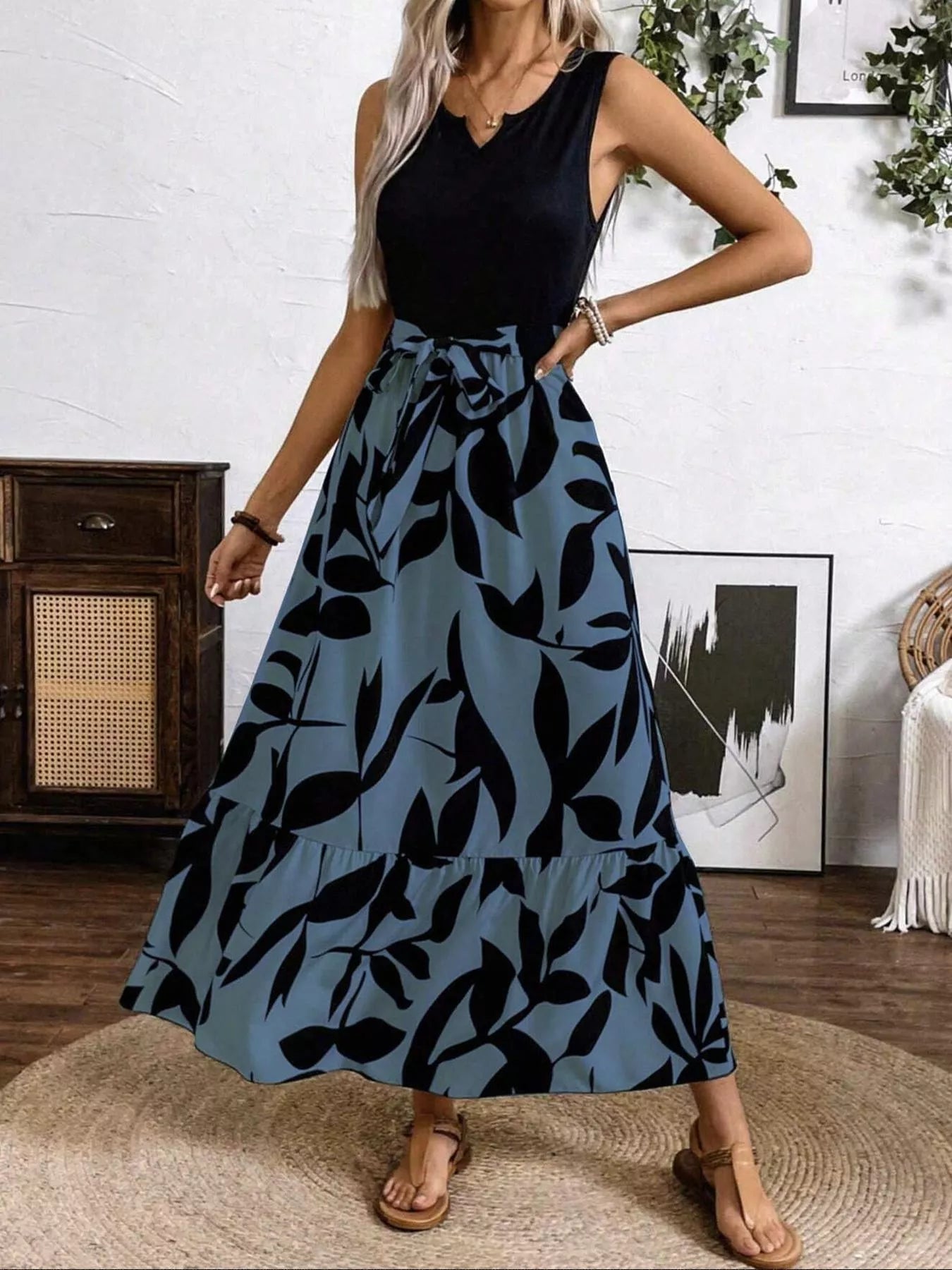 Woman wearing a black top and blue leaf-patterned skirt in a room with decor elements.