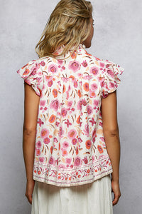 Woman wearing a floral blouse with ruffled sleeves against a gray background