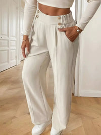 Person wearing a white outfit with wide-leg pants in an indoor setting