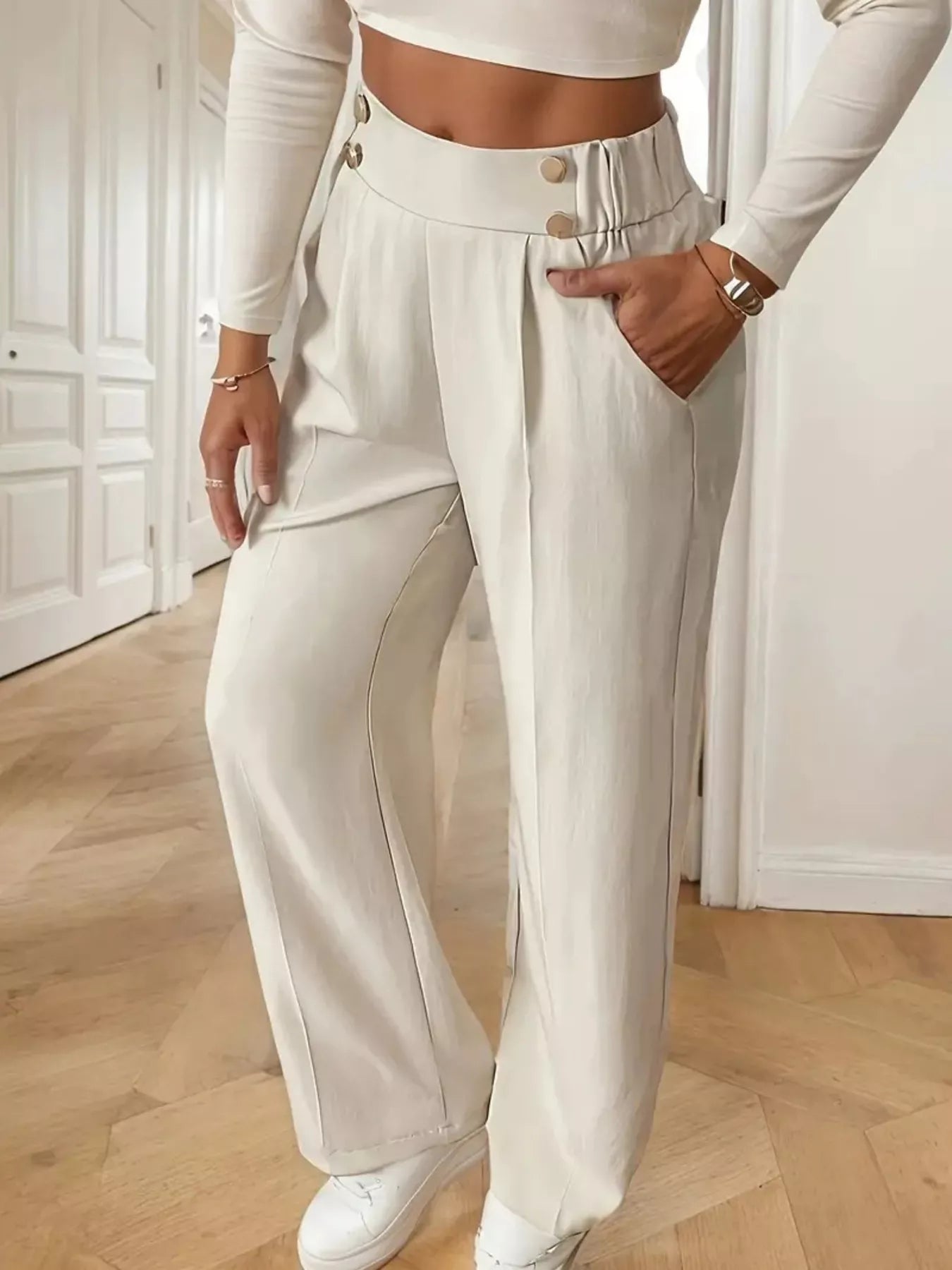 Person wearing a white outfit with wide-leg pants in an indoor setting