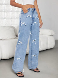 Blue jeans with white bow designs worn by a person in a minimalistic room.