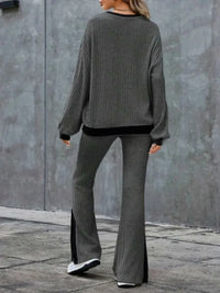 Person wearing a gray sweater and flared pants against a gray wall.
