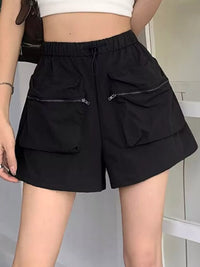 Black shorts with zippers worn by a person on a neutral background