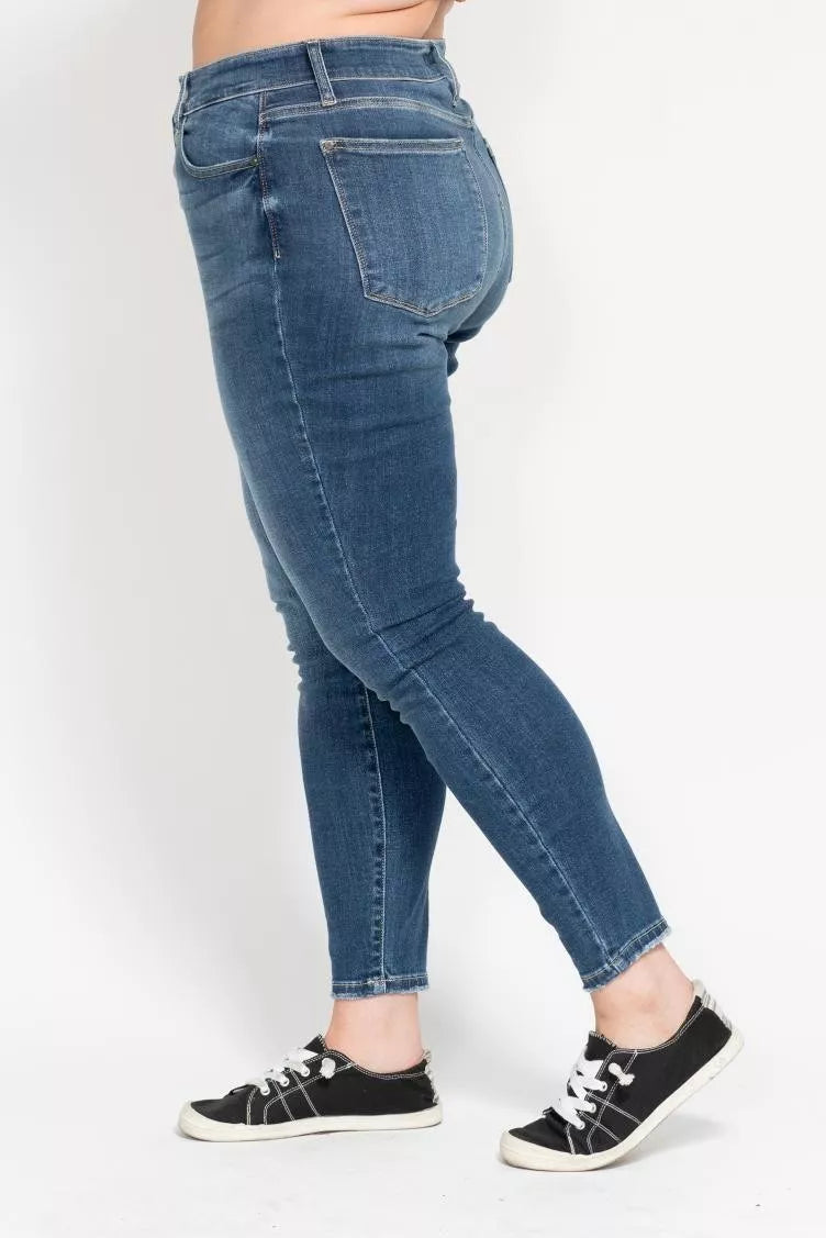 Person wearing blue jeans and black sneakers on a white background