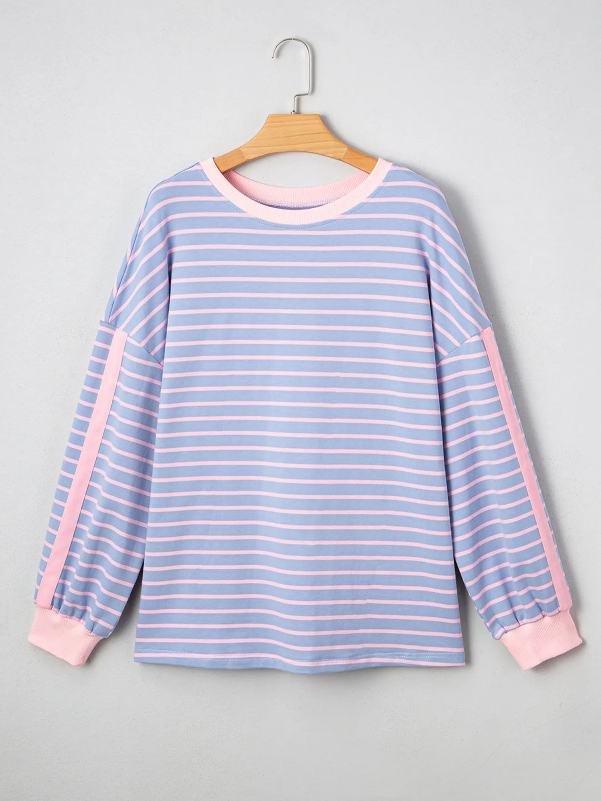 Blue and pink striped shirt on a hanger against a gray background