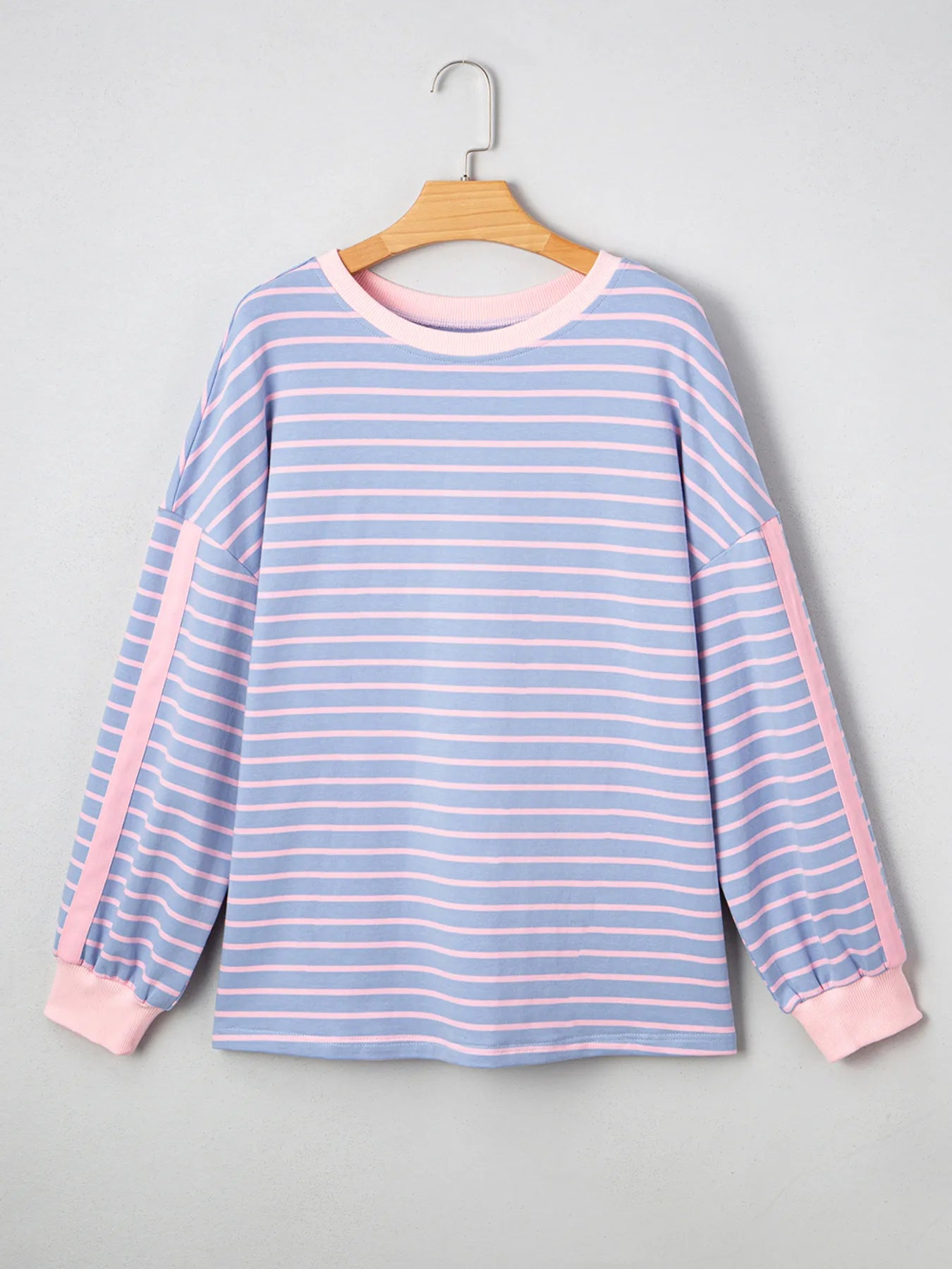 Blue and pink striped shirt on a hanger against a gray background