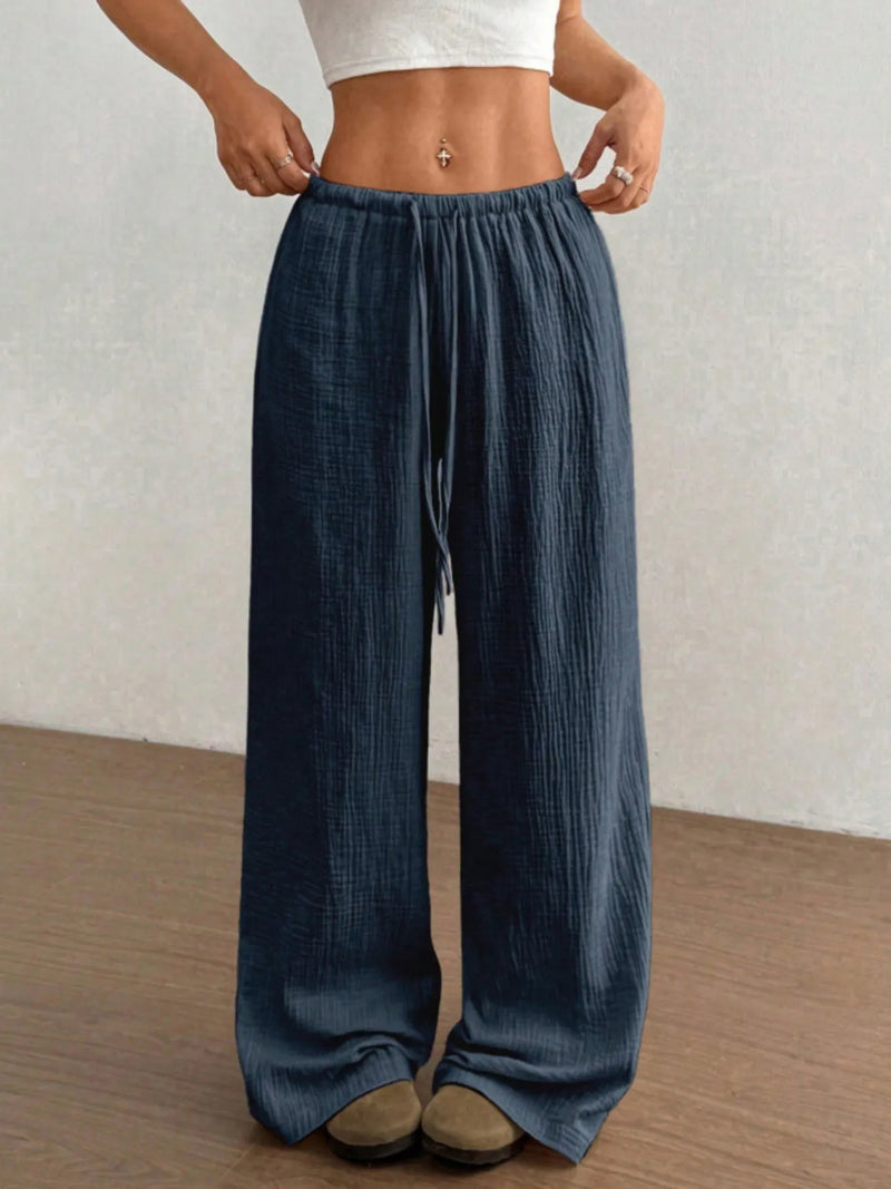 Person wearing blue wide-leg pants with a plain background