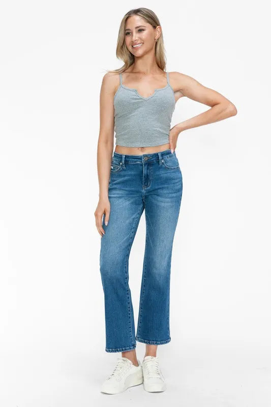 Woman wearing a gray tank top and blue jeans on a white background