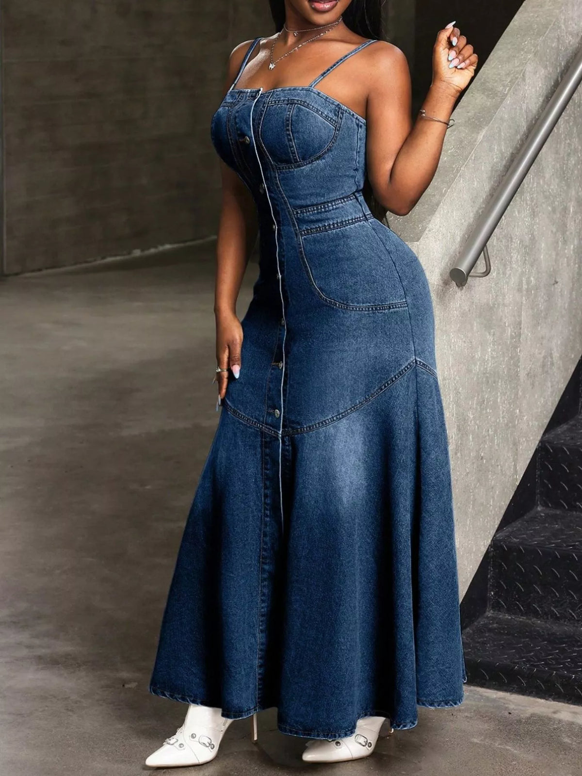 Woman wearing a long denim dress standing on a staircase.