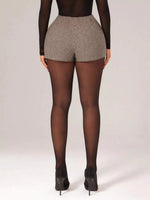 Person wearing a patterned short and black tights on a plain background