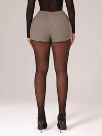 Person wearing a patterned short and black tights on a plain background