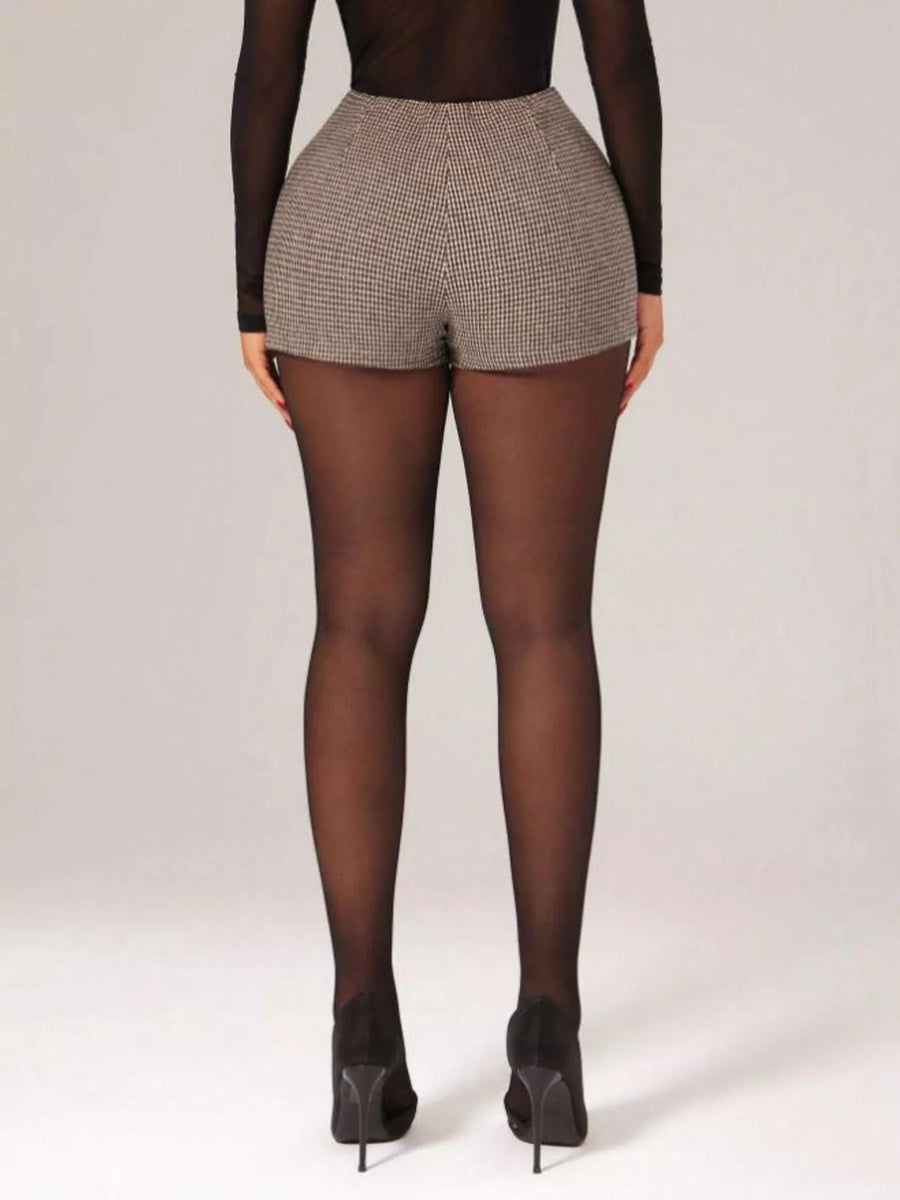 Person wearing a patterned short and black tights on a plain background