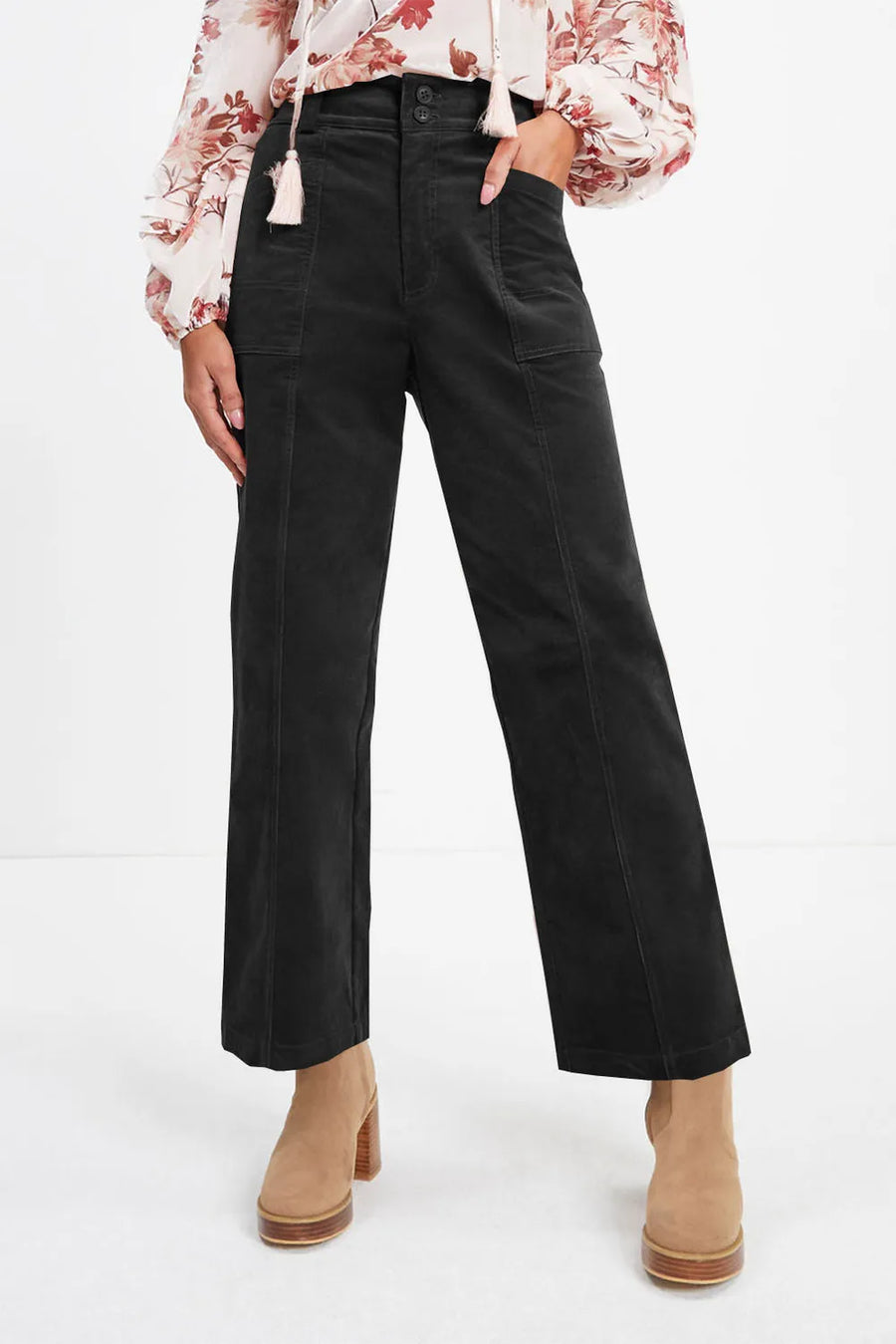 Person wearing black high-waisted pants with a floral blouse on a white background