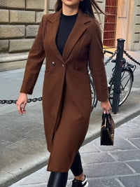 Person wearing a brown coat walking on a street.