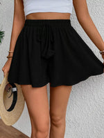Person wearing a black skirt and white top against a light background