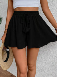 Person wearing a black skirt and white top against a light background