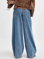 Blue wide-leg jeans worn with a brown jacket on a white background