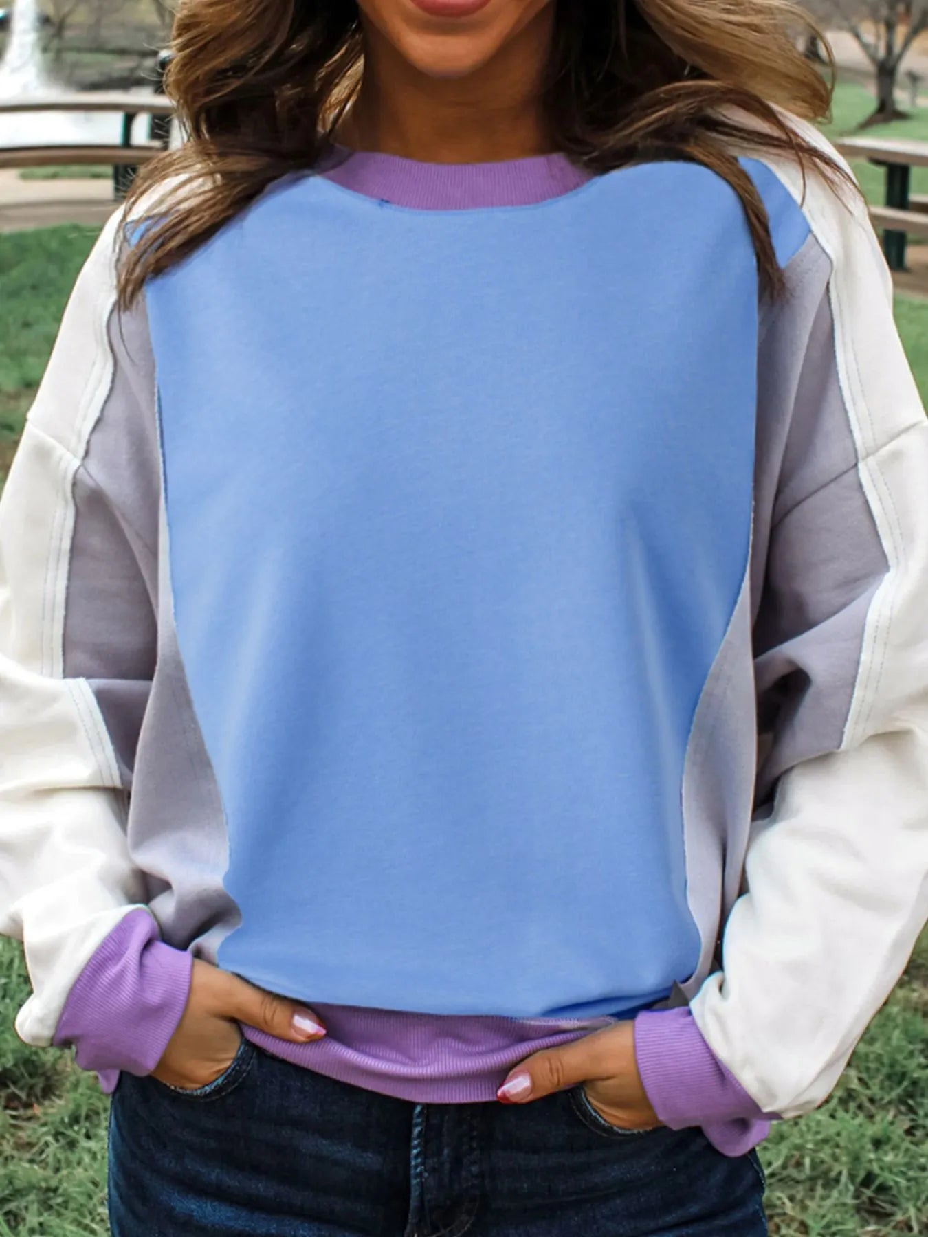 Person wearing a colorful sweater with a blue, purple, and gray design.