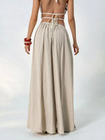 Person wearing a beige wide-leg pants and a white top with thin straps on a white background