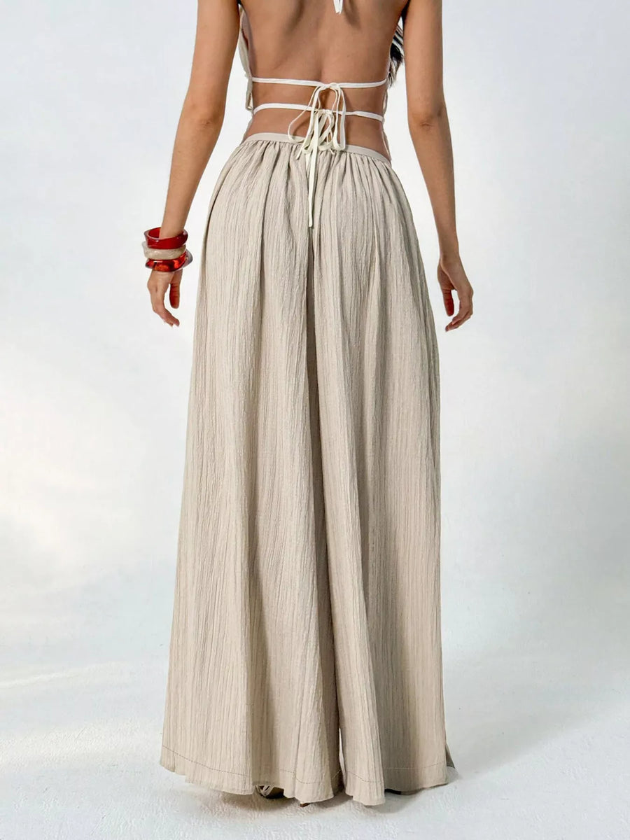 Person wearing a beige wide-leg pants and a white top with thin straps on a white background