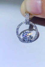 Silver ring with a central gemstone held by a hand against a light background