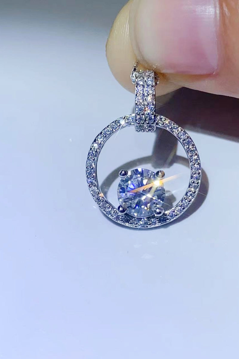 Silver ring with a central gemstone held by a hand against a light background