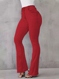 Red pants worn by a person against a gray concrete wall.