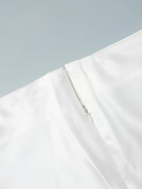 Close-up of a white garment with a zipper on a light gray background