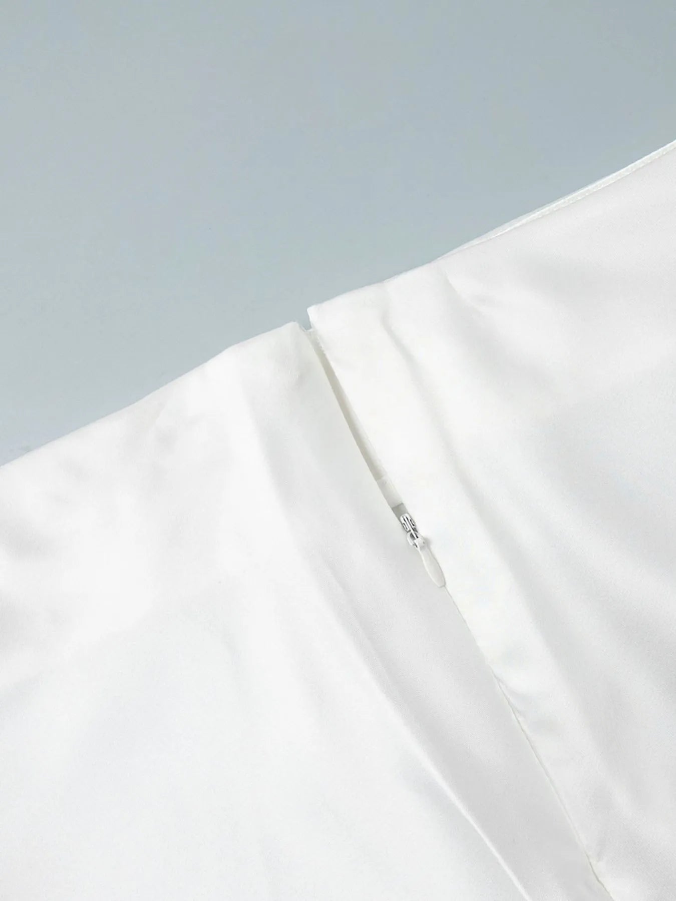Close-up of a white garment with a zipper on a light gray background