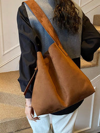 Person holding a brown leather bag indoors