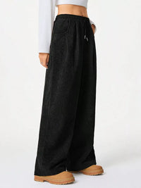 Black wide-leg pants worn by a person on a white background