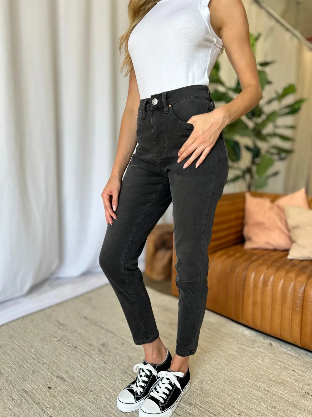 Person wearing black pants and white sneakers in a living room setting