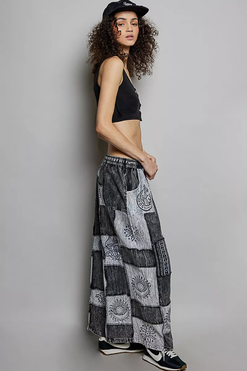 Woman wearing a black crop top and patterned long skirt against a plain background