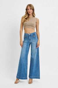 Woman wearing a beige crop top and blue jeans on a white background