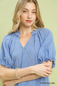 Woman wearing a blue blouse with ruffled sleeves on a light green background