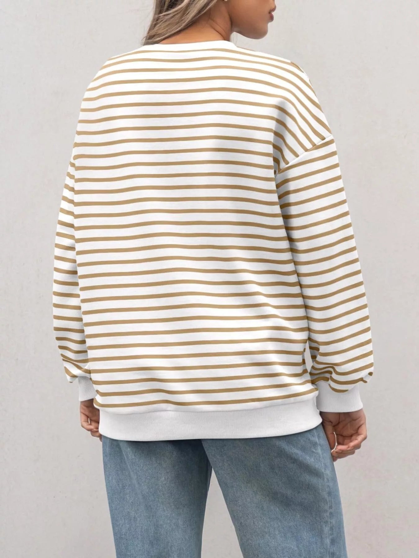 Person wearing a striped sweater and jeans on a plain background